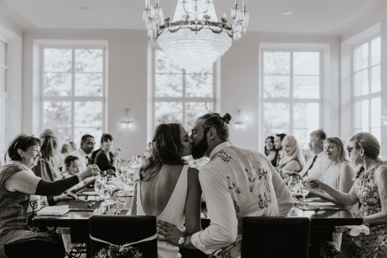 Brautpaar küsst sich bei Tisch