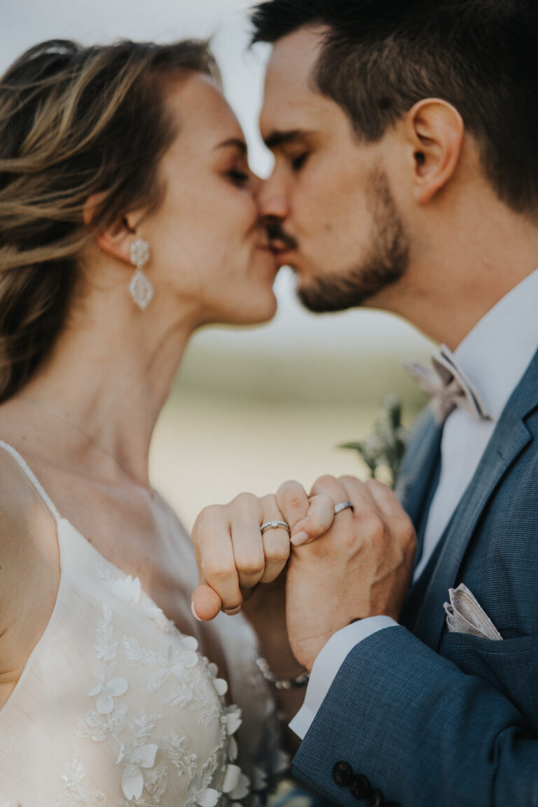 Das Brautpaar zeigt die Eheringe und küsst sich