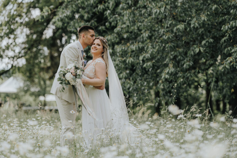 Brautpaar posiert auf einer Blumenwiese