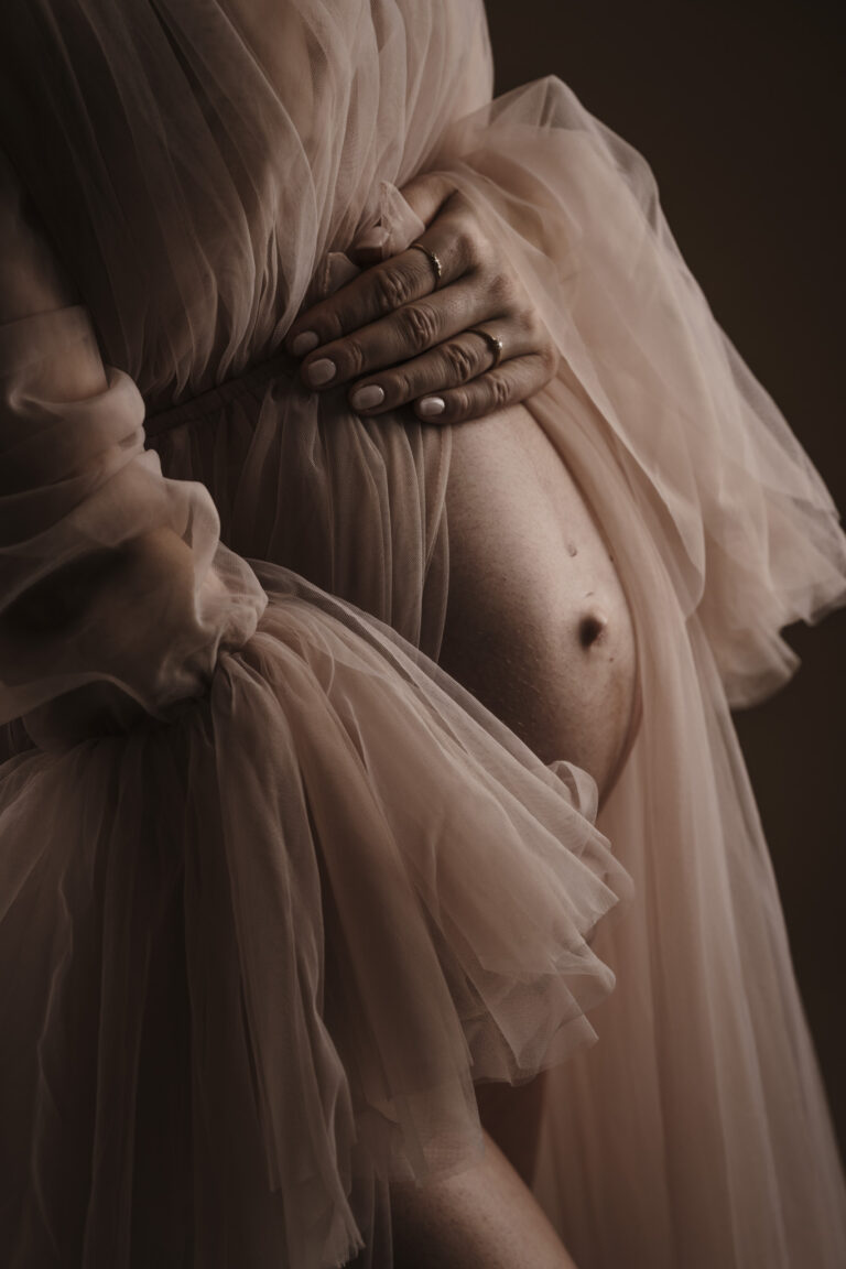 Schwangere Frau posiert mit ihrem Partner in Babybauchkleid